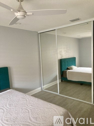 A bedroom with a bed, mirror, and ceiling fan.