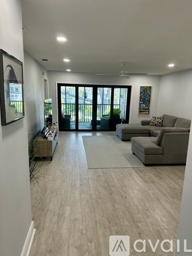 A living room with a grey couch and a rug in front of a sliding glass door.