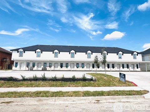 A white building with a black roof and a sign in front.