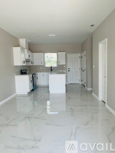 A kitchen with white cabinets and a marble floor.