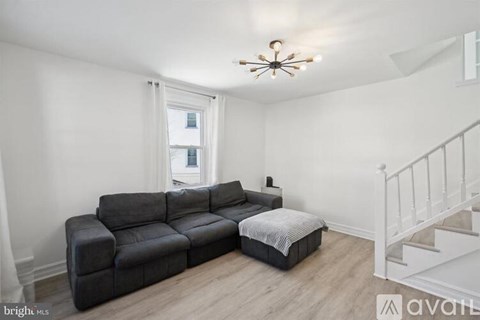 A living room with a black couch and a white staircase.