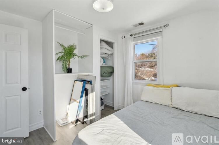 A bedroom with a bed, a plant, and a window with a view of the outdoors.