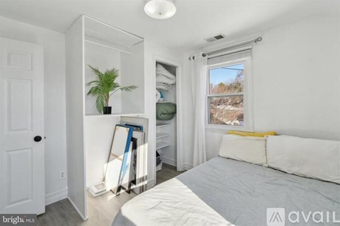 A bedroom with a bed, a plant, and a window with a view of the outdoors.