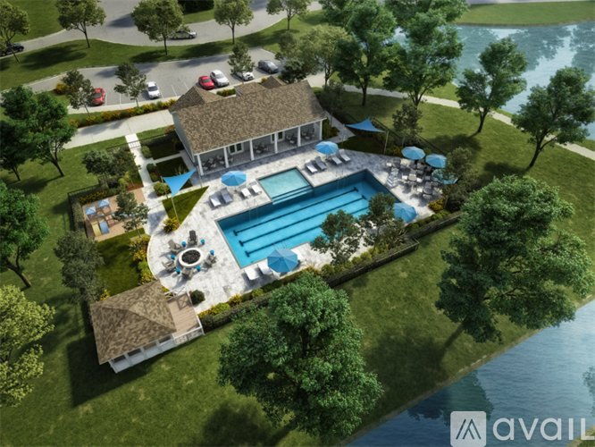 A large outdoor swimming pool surrounded by a grassy area and trees.