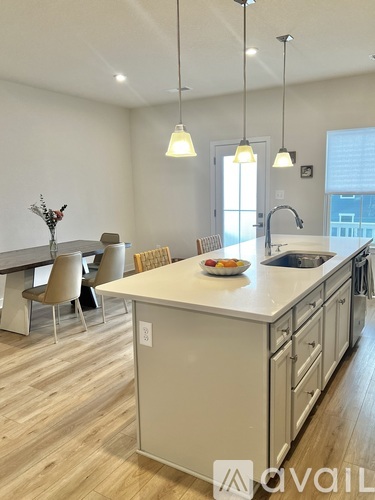 A kitchen with a table and chairs and a bowl of fruit on the counter.