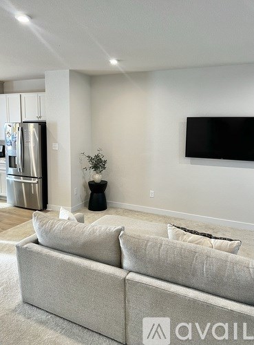 A modern living room with a grey couch and a flat screen TV mounted on the wall.