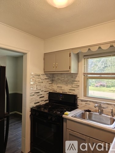 A kitchen with a black stove top oven and a sink.