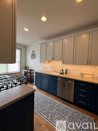 A kitchen with dark blue cabinets and a patterned rug on the floor.