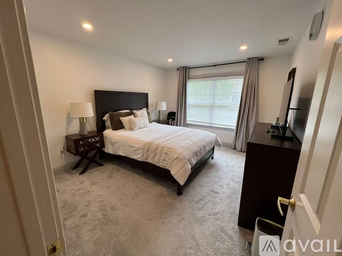 A bedroom with a large bed, a nightstand with a lamp, and a television.