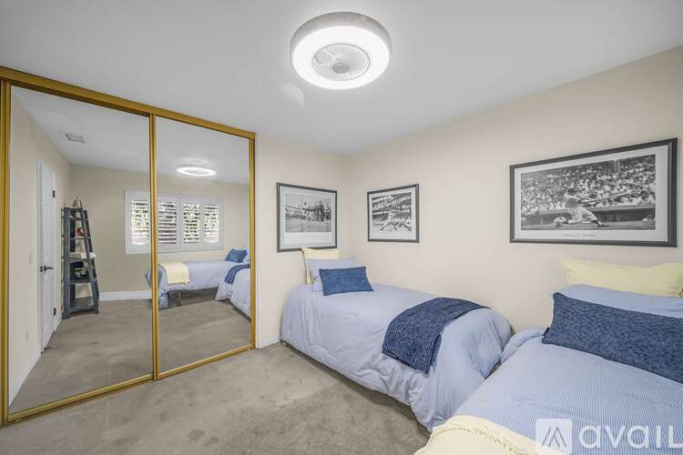 A bedroom with two beds and a mirror on the wall.