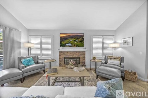 A living room with a fireplace and a painting of a mountain landscape on the wall.