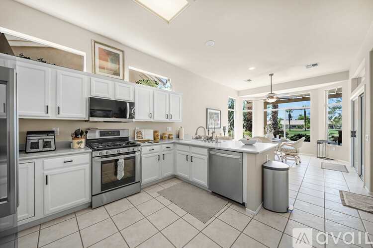 A kitchen with white cabinets and appliances, a large island, and a view of the backyard.