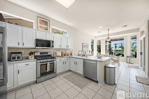 A kitchen with white cabinets and appliances, a large island, and a view of the backyard.