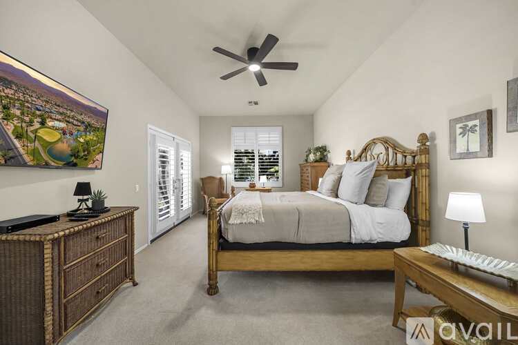 A bedroom with a large bed, a wooden dresser, and a ceiling fan.
