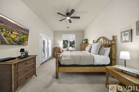 A bedroom with a large bed, a wooden dresser, and a ceiling fan.