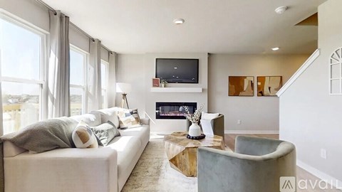 A living room with a white couch, a fireplace, and a television mounted on the wall.