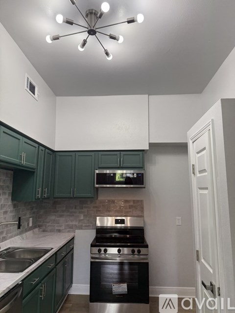 A kitchen with green cabinets and a stainless steel oven.