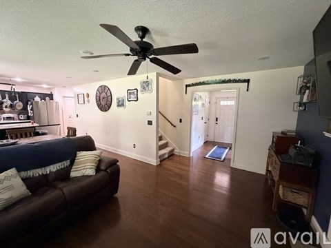 A living room with a brown couch and a ceiling fan.