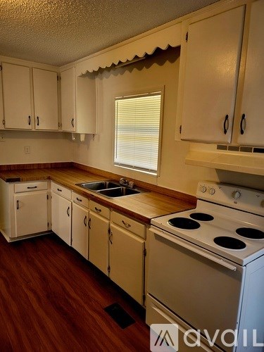 A kitchen with white cabinets and a white stove top oven.