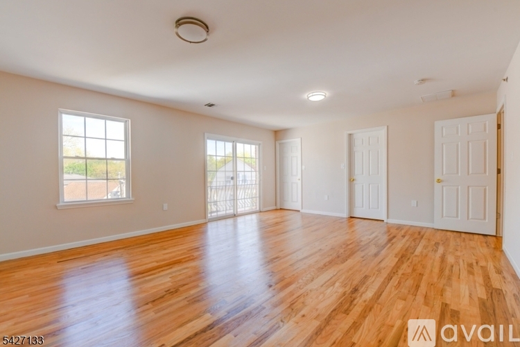 A spacious room with wooden floors and white walls.