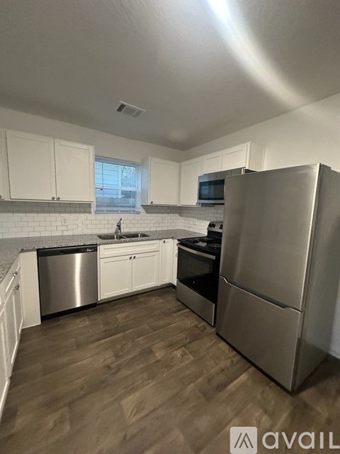 A kitchen with white cabinets and a wooden floor.