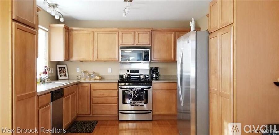 A kitchen with wooden cabinets and a stainless steel refrigerator.
