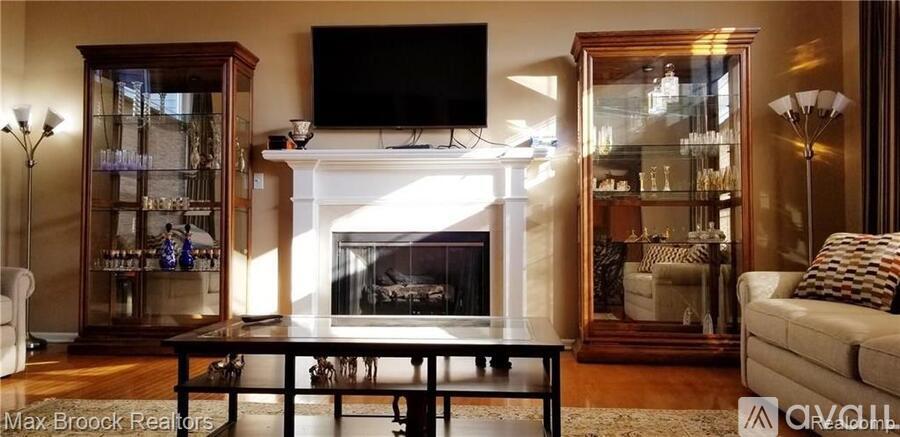 A living room with a fireplace and a television mounted above it.