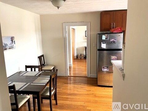A kitchen with a refrigerator, table and chairs.