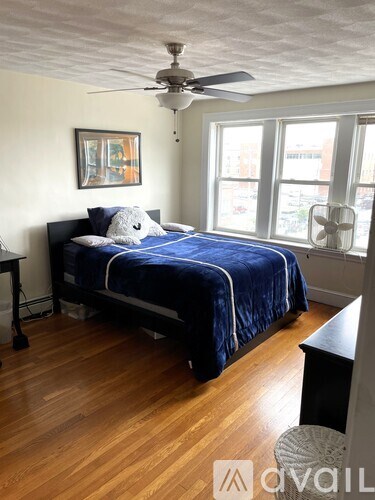 A bedroom with a bed, a ceiling fan, and a window.