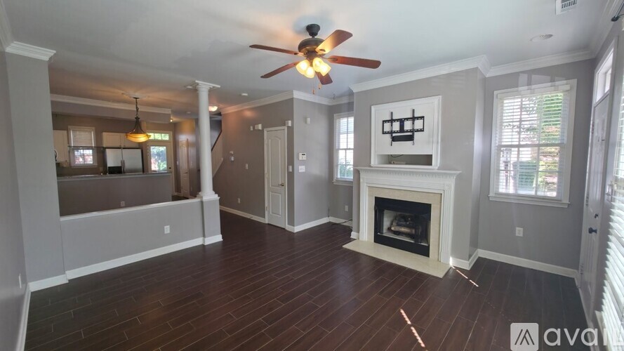 A spacious living room with a fireplace and a ceiling fan.