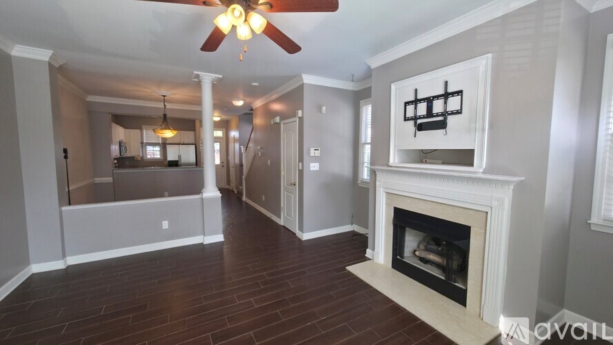 A living room with a fireplace and a ceiling fan.