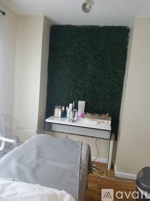 A room with a grey couch and a green wallpaper.