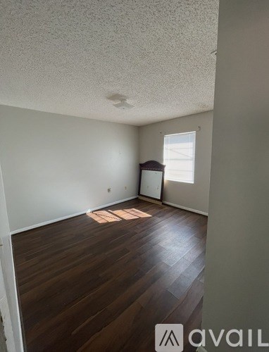 A room with wooden floors and a window letting in sunlight.