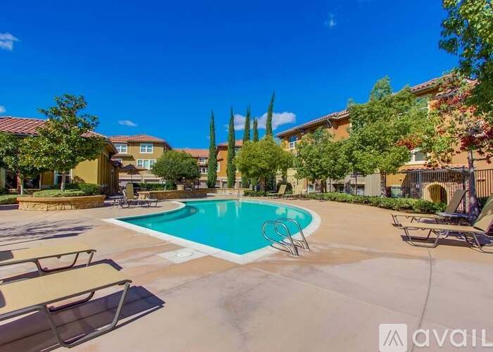 A swimming pool surrounded by lounge chairs and palm trees.