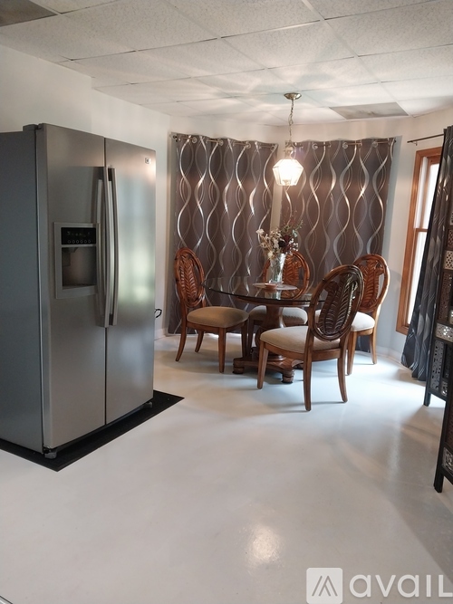 A kitchen with a stainless steel refrigerator and a dining table with chairs.
