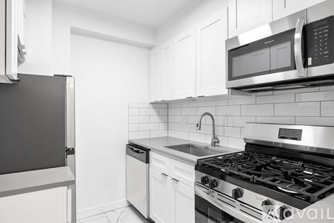 A kitchen with a black stove top oven and white cabinets.