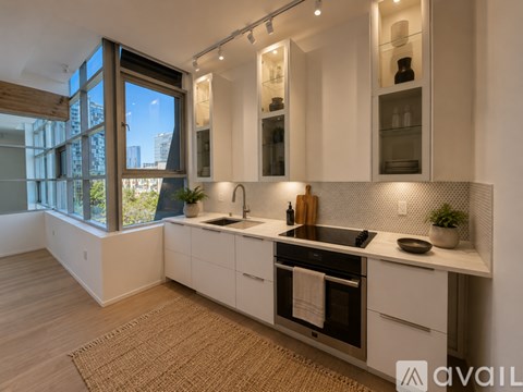 A modern kitchen with white cabinets and a large window.