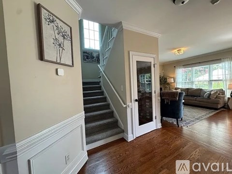 A living room with a staircase and a painting on the wall.