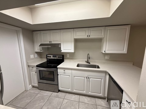 A kitchen with white cabinets and a black countertop.