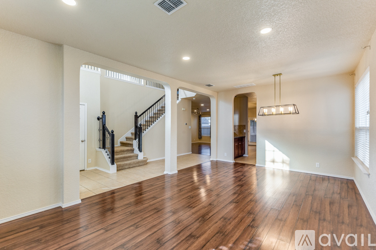 A spacious living room with wooden floors and a staircase leading to the upper level.