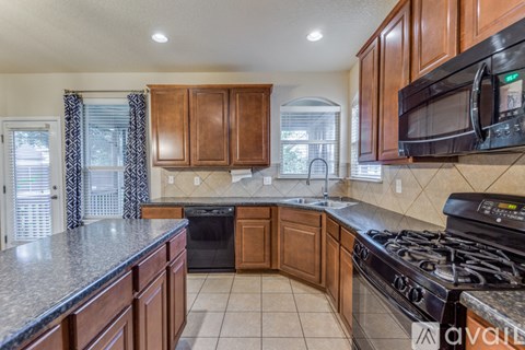 A kitchen with dark wood cabinets and a black stove top oven.