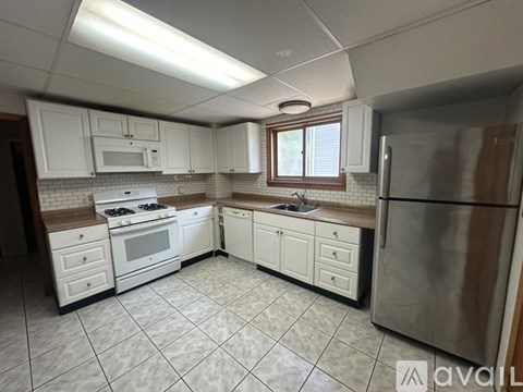 A kitchen with white cabinets and a tile floor.