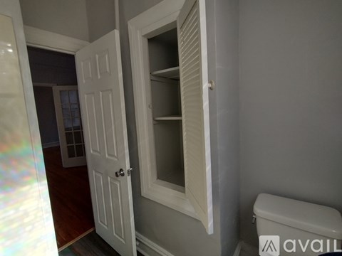 A white door is open to a small room with a toilet.