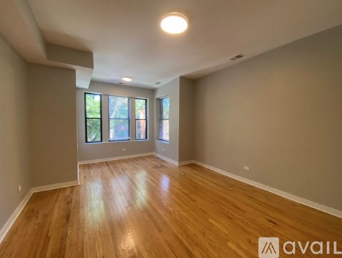 A spacious room with wooden flooring and large windows.