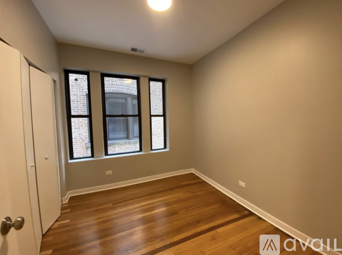 A room with wooden floors and a window with a view of a brick building.