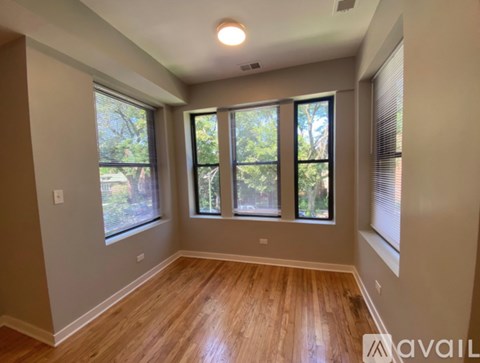 A room with wooden floors and three windows.