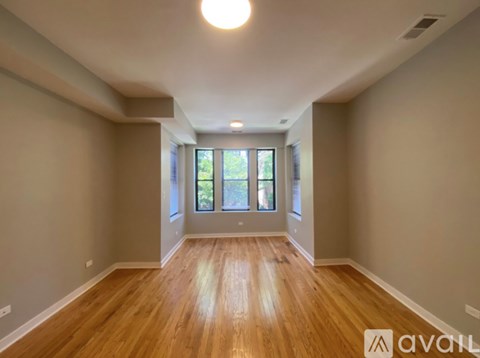 A spacious room with wooden flooring and a large window.