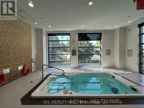 A hot tub in a room with a wallpapered wall and a glass door leading outside.