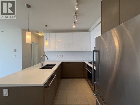 A modern kitchen with a stainless steel refrigerator and white countertops.