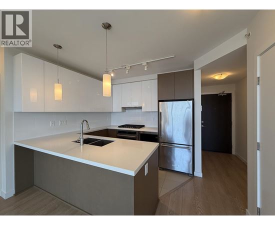 A modern kitchen with a white countertop and stainless steel appliances.